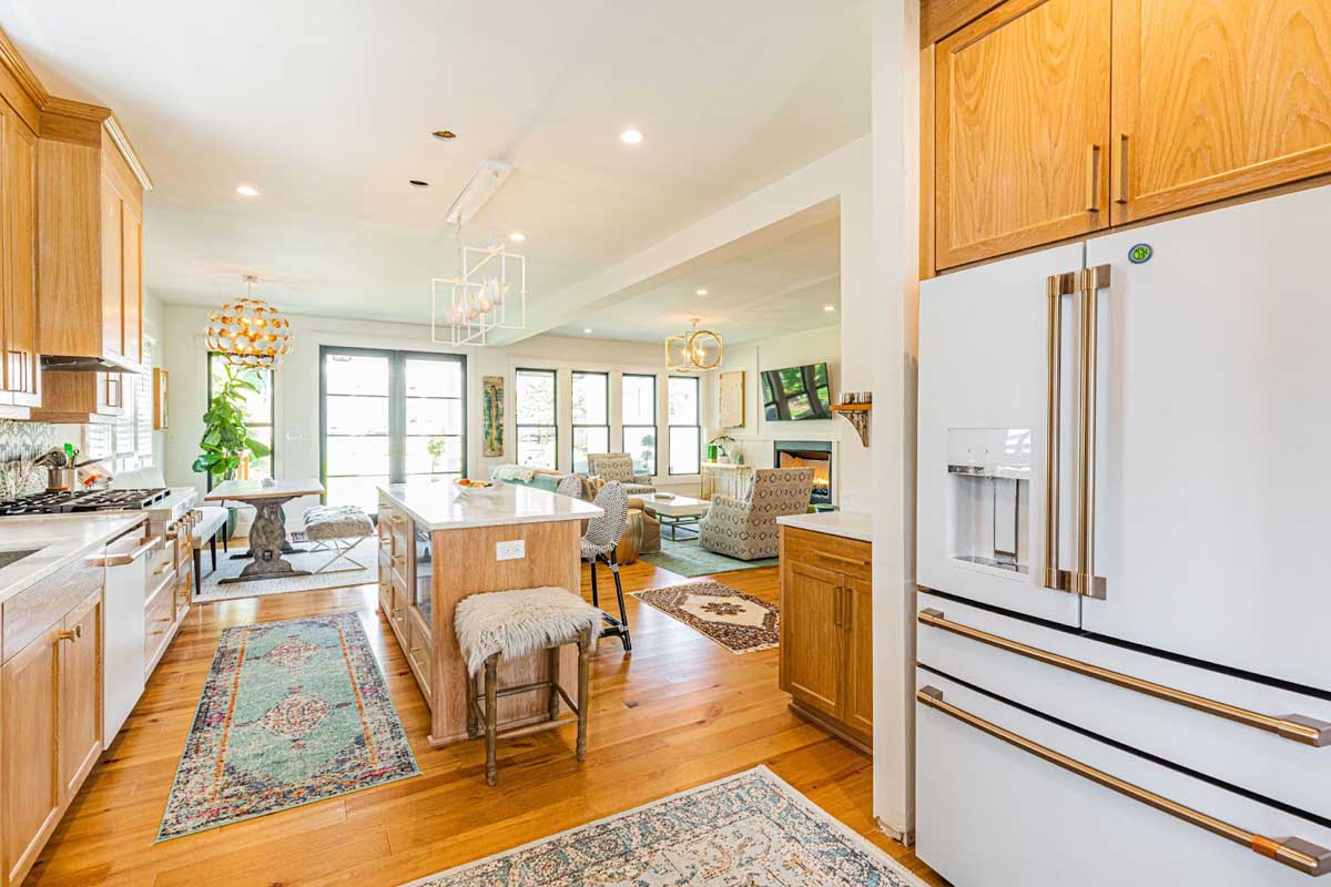 Beautiful kitchen remodel by BK Martin showing refrigerator on right and lots of natural light through glass windows and doors.