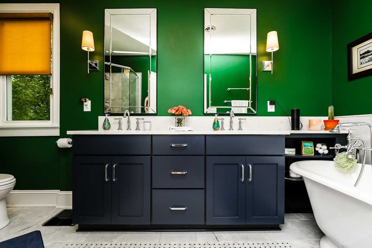Full-bath showing green walls with two mirrors and a bathtub.
