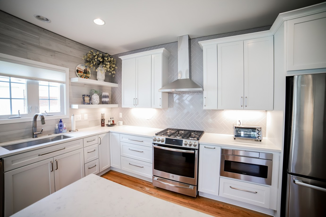 Updated kitchen cabinets and stainless steel appliances featuring a range hood for ventilation