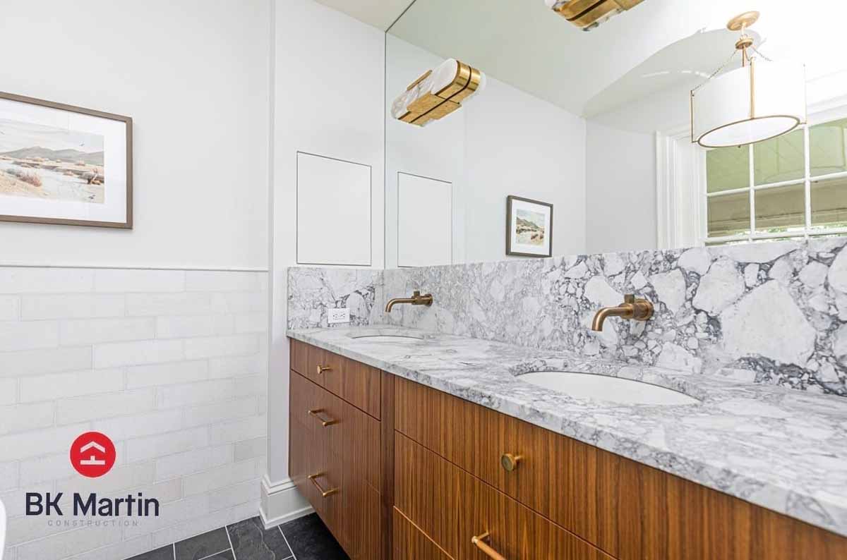 Wood double bathroom vanity with stone countertop and backsplash and black tile floor