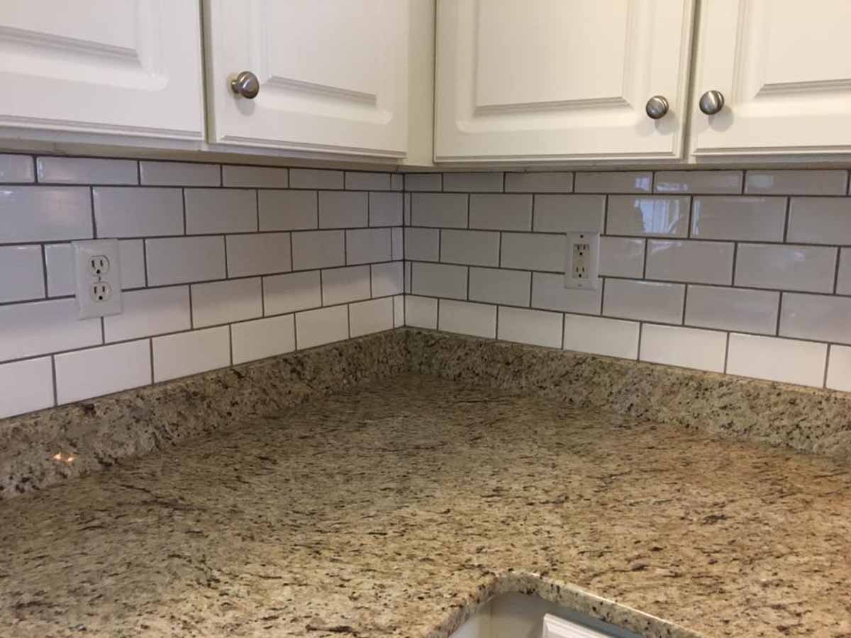 Timeless white wood cabinets, white subway tile backsplash with dark grout, and a neutral tone granite countertop