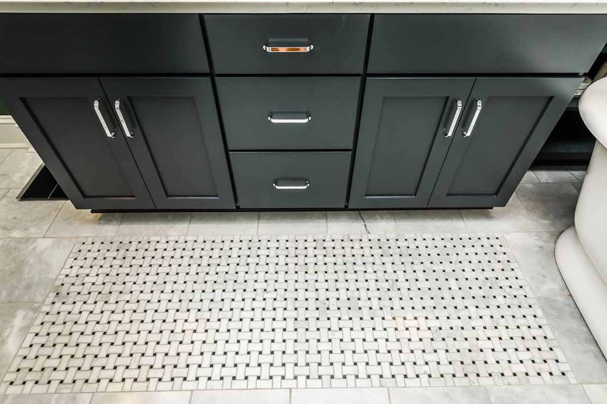 Navy blue bathroom vanity and tile floor featuring a tile inlay design