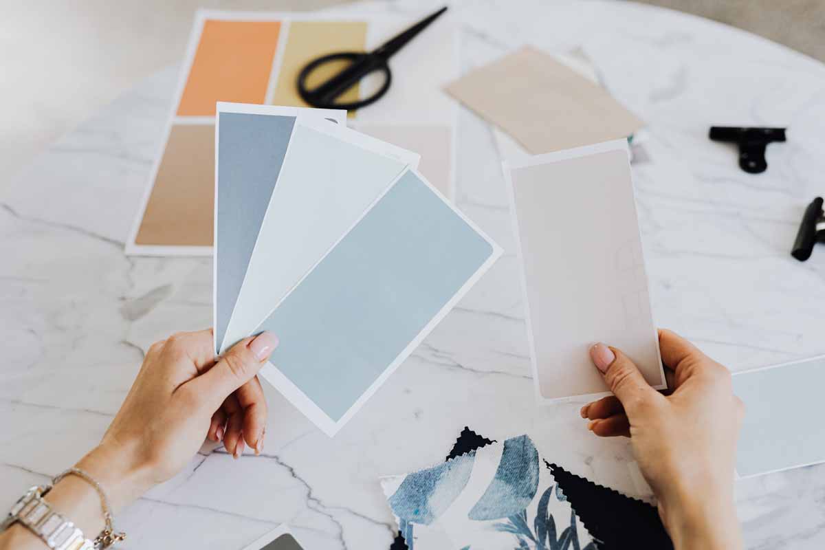 Woman holding paint sample chips in shades of blue and beige