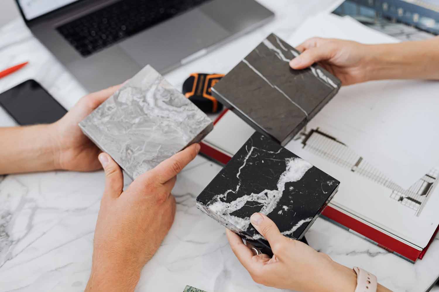 Two people holding square samples of countertops in different materials