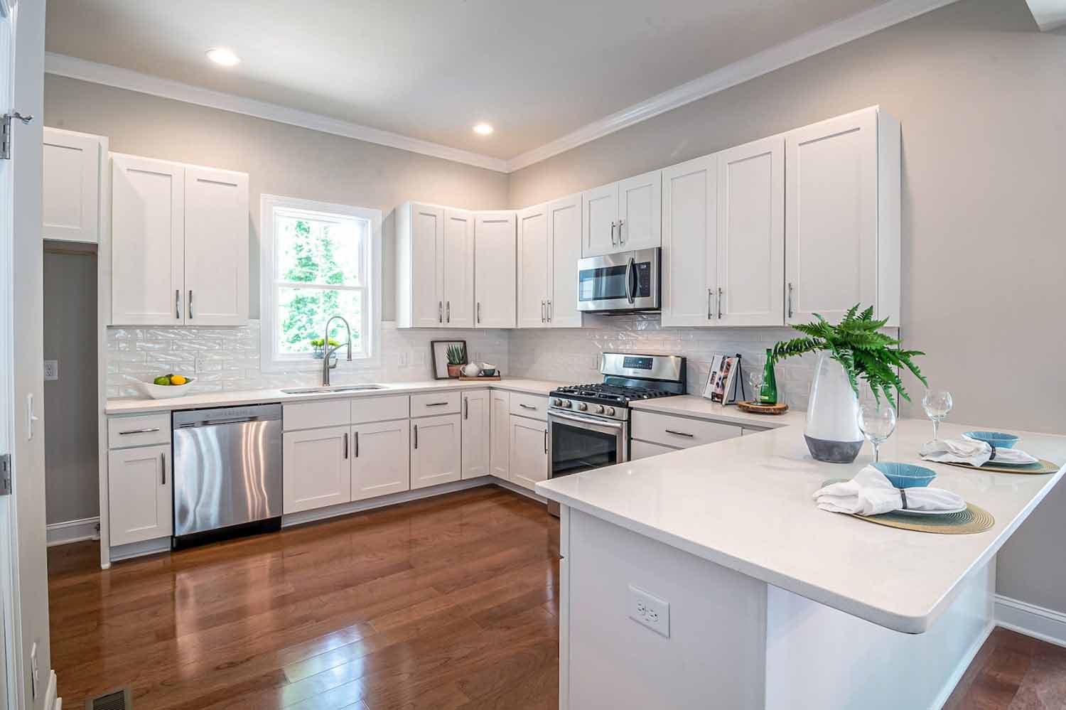 L-shaped kitchen with white cabinets that also incorporates a peninsula.