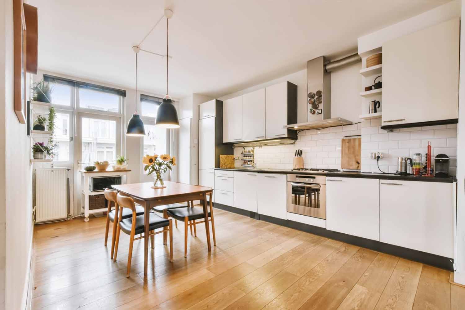 Modern one wall kitchen layout with a small table in the middle of the room, pendant lights above