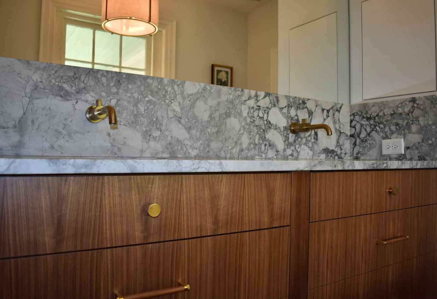 BK Martin bathroom featuring a wood double vanity and marble counter with matching backsplash